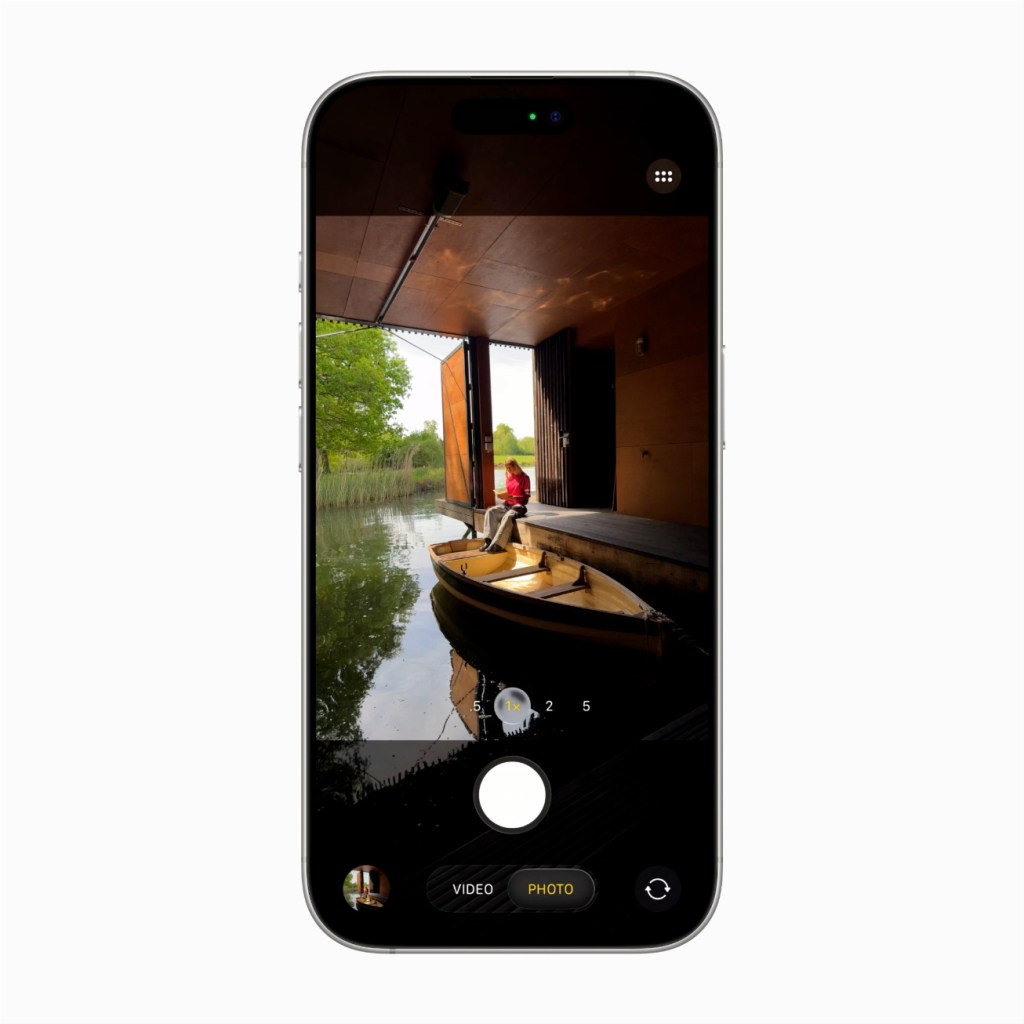 iPhone 화면에서 촬영 중인 모습으로, 카메라 앱 인터페이스가 보이며, 개인이 보트에 앉아 있는 배경이 담겨 있다.
