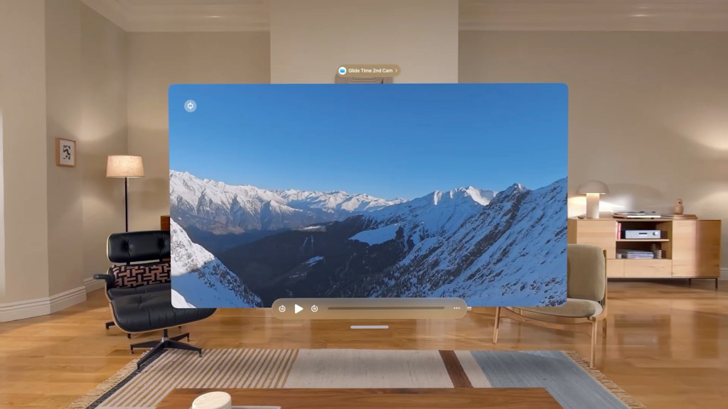 A virtual representation of a snow-covered mountain landscape displayed in a modern living room environment, featuring a comfortable chair and a table.