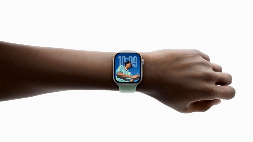 A close-up of a person's arm wearing an Apple Watch displaying a vibrant watch face with a time reading of 10:09.