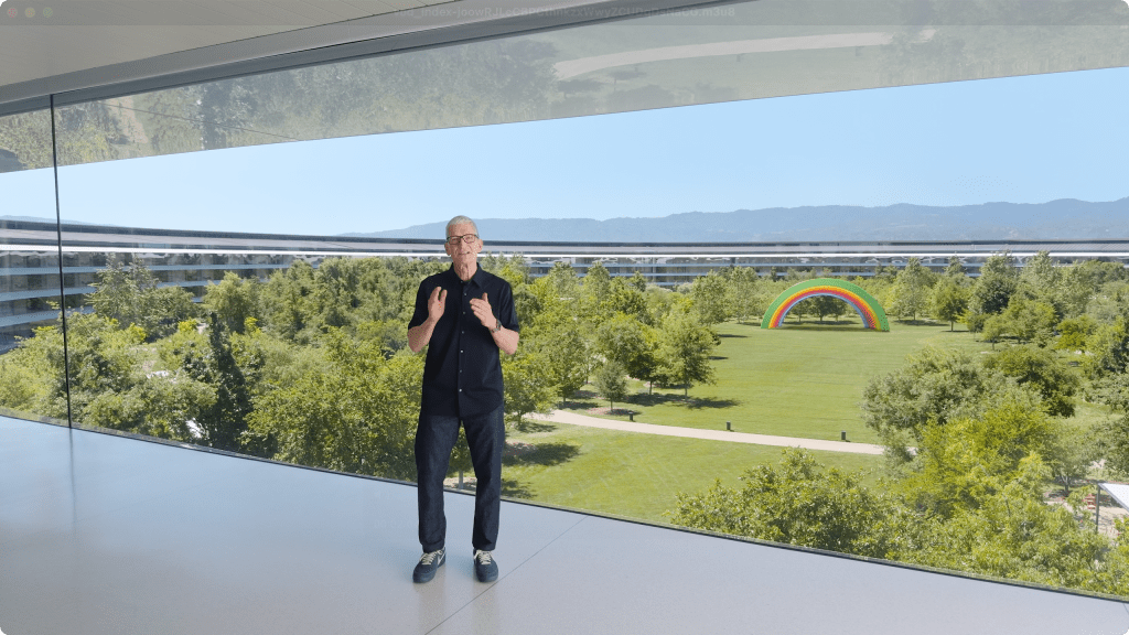 Apple Park에서 기조 강연을 하는 발표자와 배경의 푸른 잔디밭과 무지개 조형물