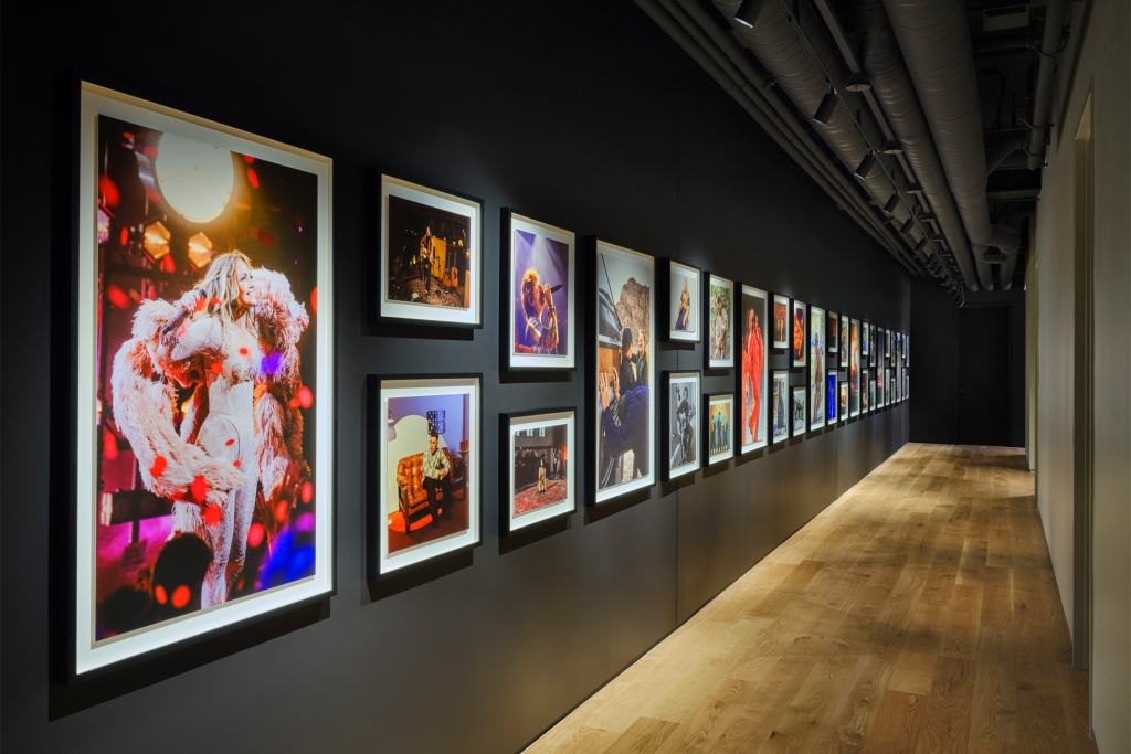 A hallway featuring framed photographs of musicians, showcasing vibrant visuals on a dark wall.