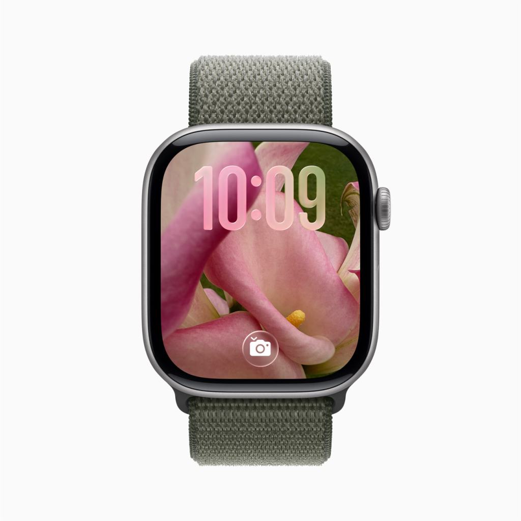 Apple Watch의 화면에 분홍색 꽃 이미지가 표시된 디자인, 시계의 시간은 10:09이며, 회색 밀리터리 스타일 스트랩이 보인다.