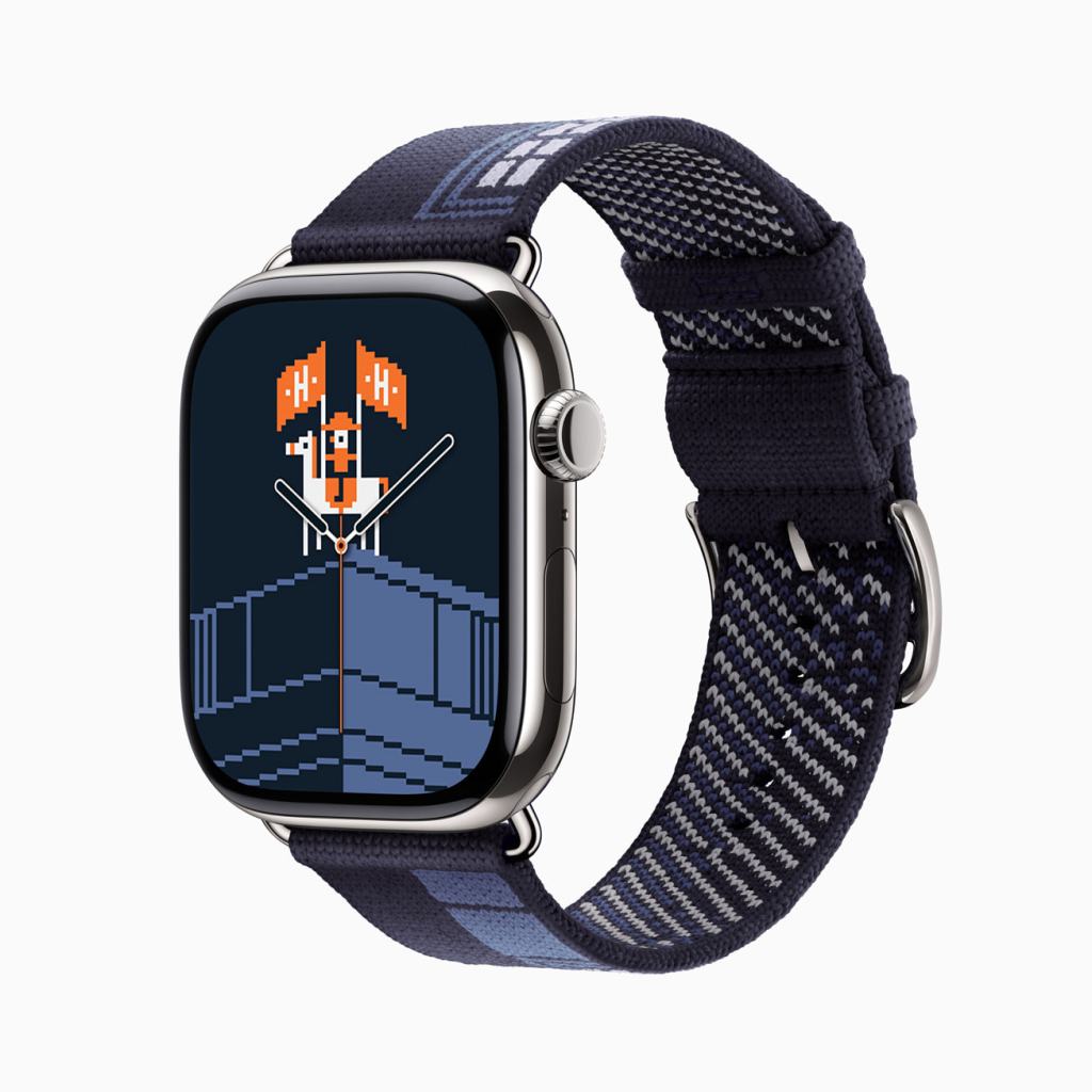 Apple Watch Series 11의 측면 모습, 디스플레이에는 픽셀 아트 스타일의 캐릭터와 아이콘이 표시되어 있으며, 패턴있는 나일론 밴드가 부착되어 있다.