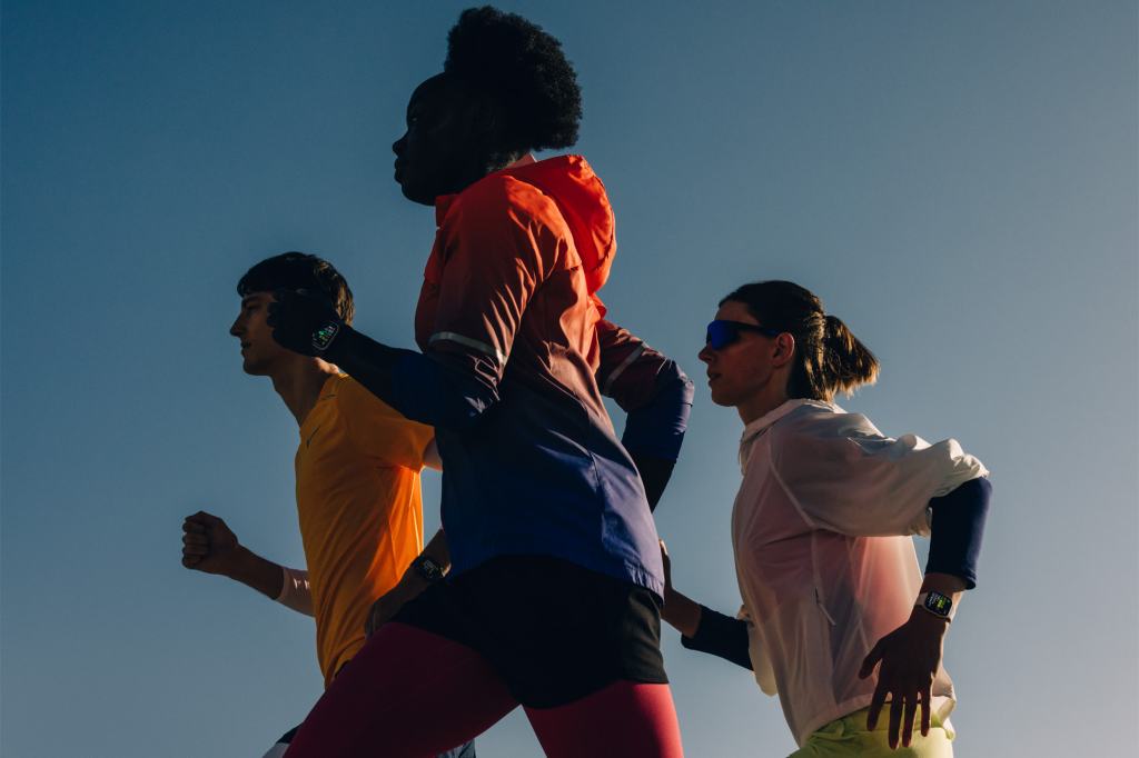 세 명의 사람이 야외에서 러닝을 하고 있는 모습으로, 각각 밝은색 의상을 입고 있으며 Apple Watch를 착용하고 있다.