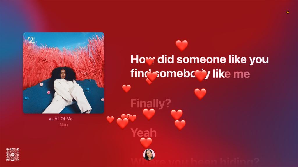 노래 'All Of Me'의 앨범 아트워크와 함께 가사 일부가 표시된 화면, 배경은 붉은 색조이며, 여러 개의 하트 이모티콘이 떠오르고 있다.