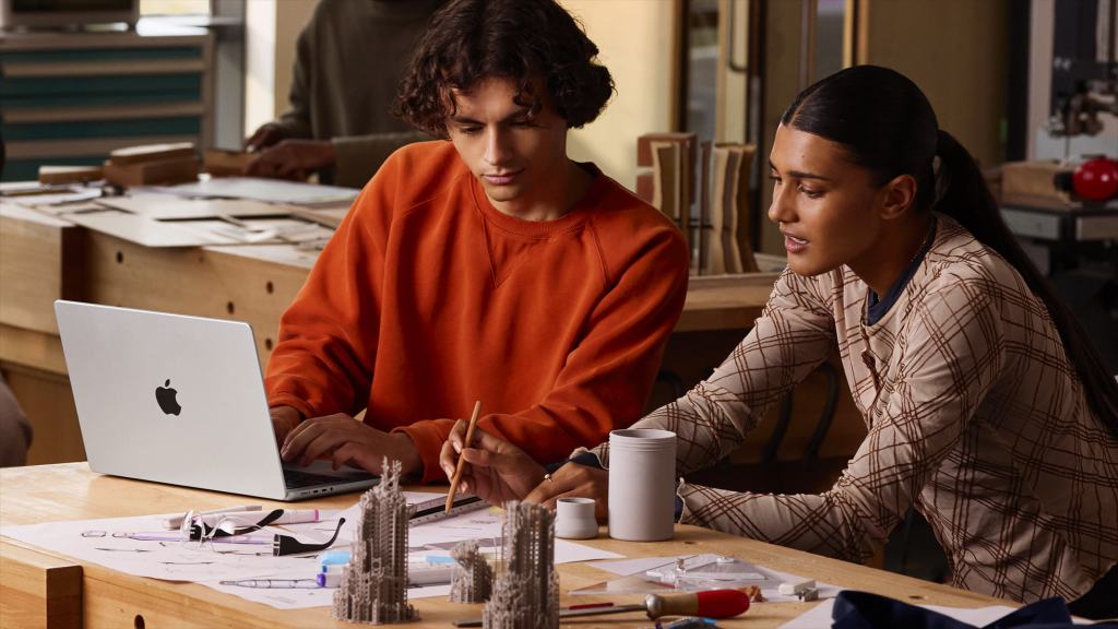 두 사람이 작업 테이블에서 MacBook Pro를 사용하며 디자인 작업을 하고 있는 모습.