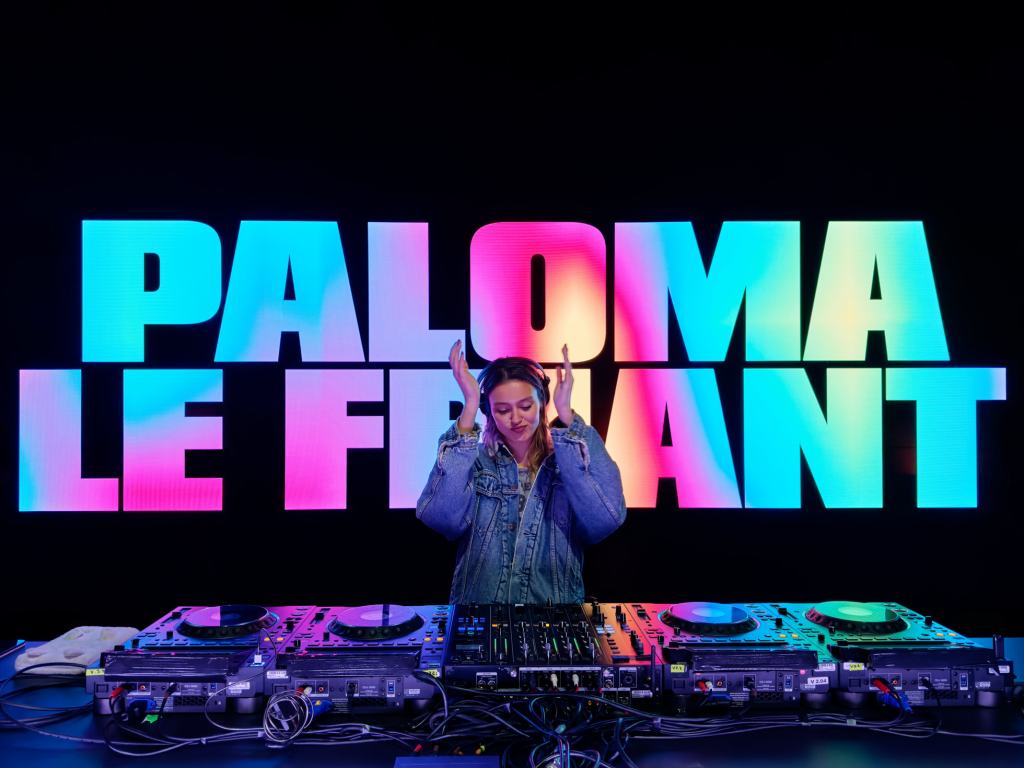 DJ가 음악을 혼합하는 모습. 배경에 'PALOMA LE FRANT'라는 다채로운 글자가 보임.