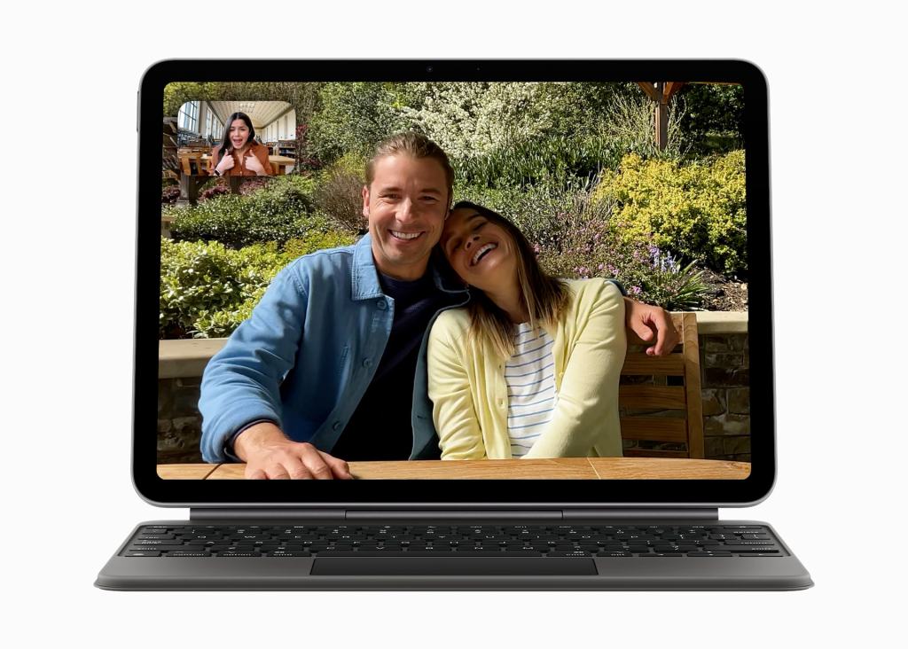 두 사람이 야외 테이블에서 웃으며 포즈를 취하고 있는 모습이 담긴 태블릿 화면, 후면에는 그들의 영상 통화 중인 또 다른 사람의 모습이 보임.